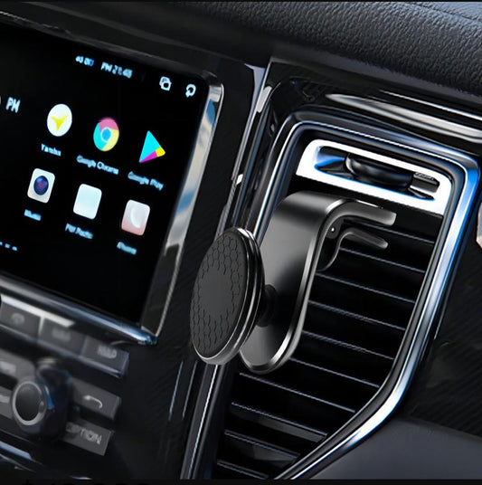 Soporte magnético negro instalado en rejilla de ventilación del carro con pantalla táctil Android visible al fondo